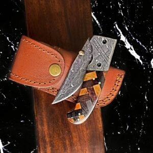 A knife with a swirled Damascus steel blade and a geometric wooden handle rests on a brown leather sheath