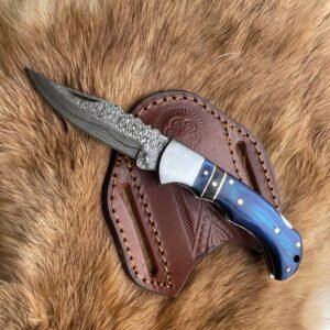 A folding knife with a patterned Damascus blade and a blue handle with brass pins rests on a tooled brown leather sheath and furry surface