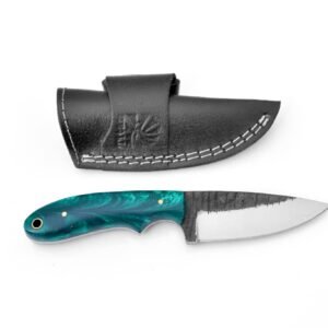 A custom knife with a swirled teal resin handle and a dark, textured blade, alongside a black leather sheath with white stitching and a spider logo