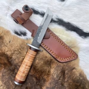 A knife with a stacked leather handle and a sawback metal blade, partially in a brown leather sheath, on a fur rug