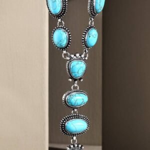 A long silver necklace with multiple oval and tear-shaped turquoise stones in ornate settings