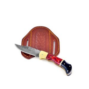 A Damascus steel folding knife with a red and black handle, resting on a brown leather sheath