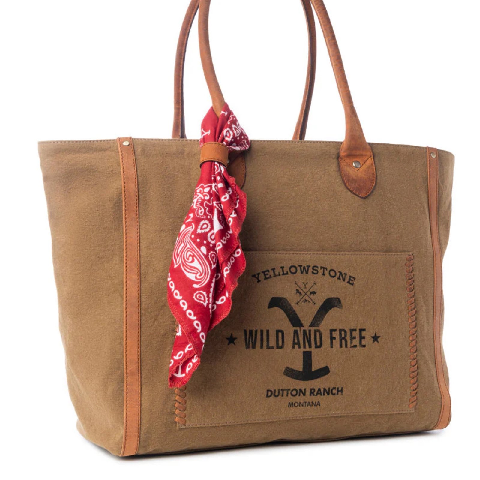 A brown canvas tote bag with leather handles, a red paisley bandana, and "Yellowstone Wild and Free Dutton Ranch Montana" text