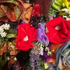 A vibrant close-up of various craft materials including red fabric flowers, metallic mesh ribbons, and small white and lavender artificial blossoms