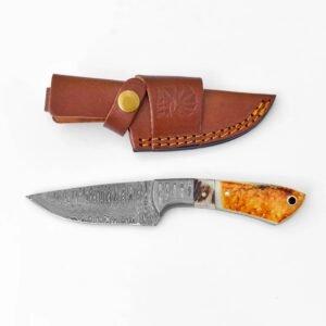 A Damascus steel knife with an orange and light-colored handle lies beside a brown leather sheath with an embossed design